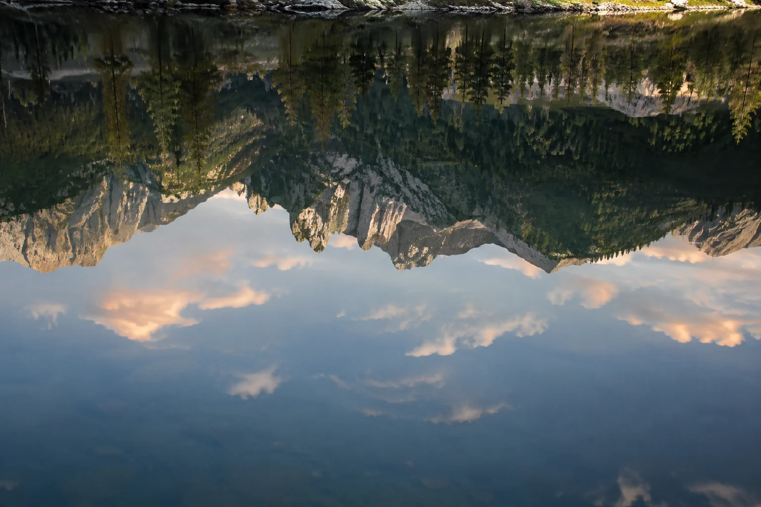 Reflejo invertido de un paisaje sobre la superficie quieta de un estanque